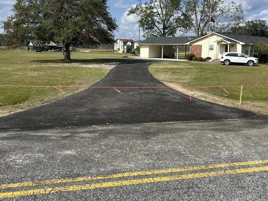 Freshly paved drive with a caution line across it in front of a home, asphalt driveways