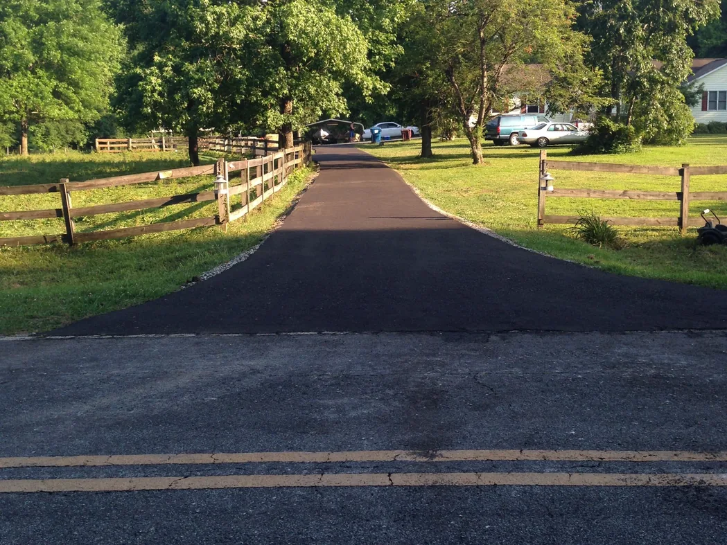 New paved drive running between wooden fences from the road, asphalt driveways