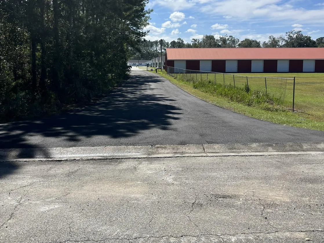 Newly paved private access road past a row of storage buildings, also a fit for chip seal