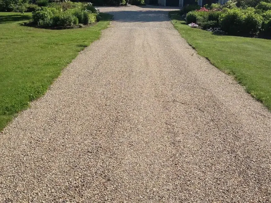 Finished tan tar and chip driveway running between two lawns, chip seal
