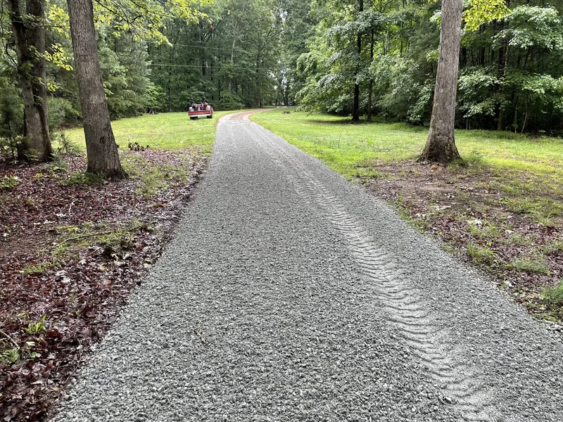 Freshly graded gravel drive running through a wooded lawn, grading