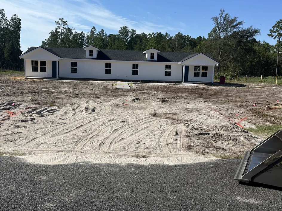 Graded sand lot with track marks in front of a new duplex, ready for paving, grading