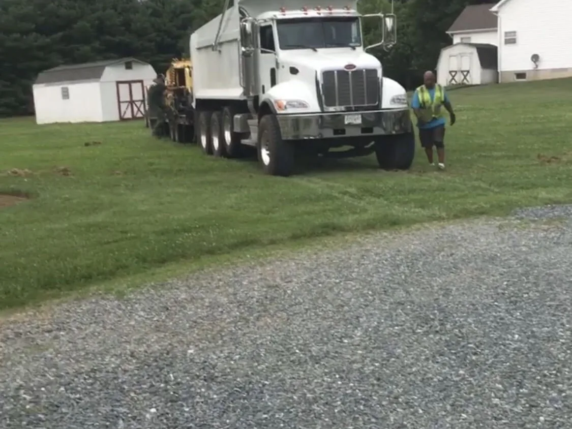 Dump truck and crew member beside a gravel drive, gravel driveways