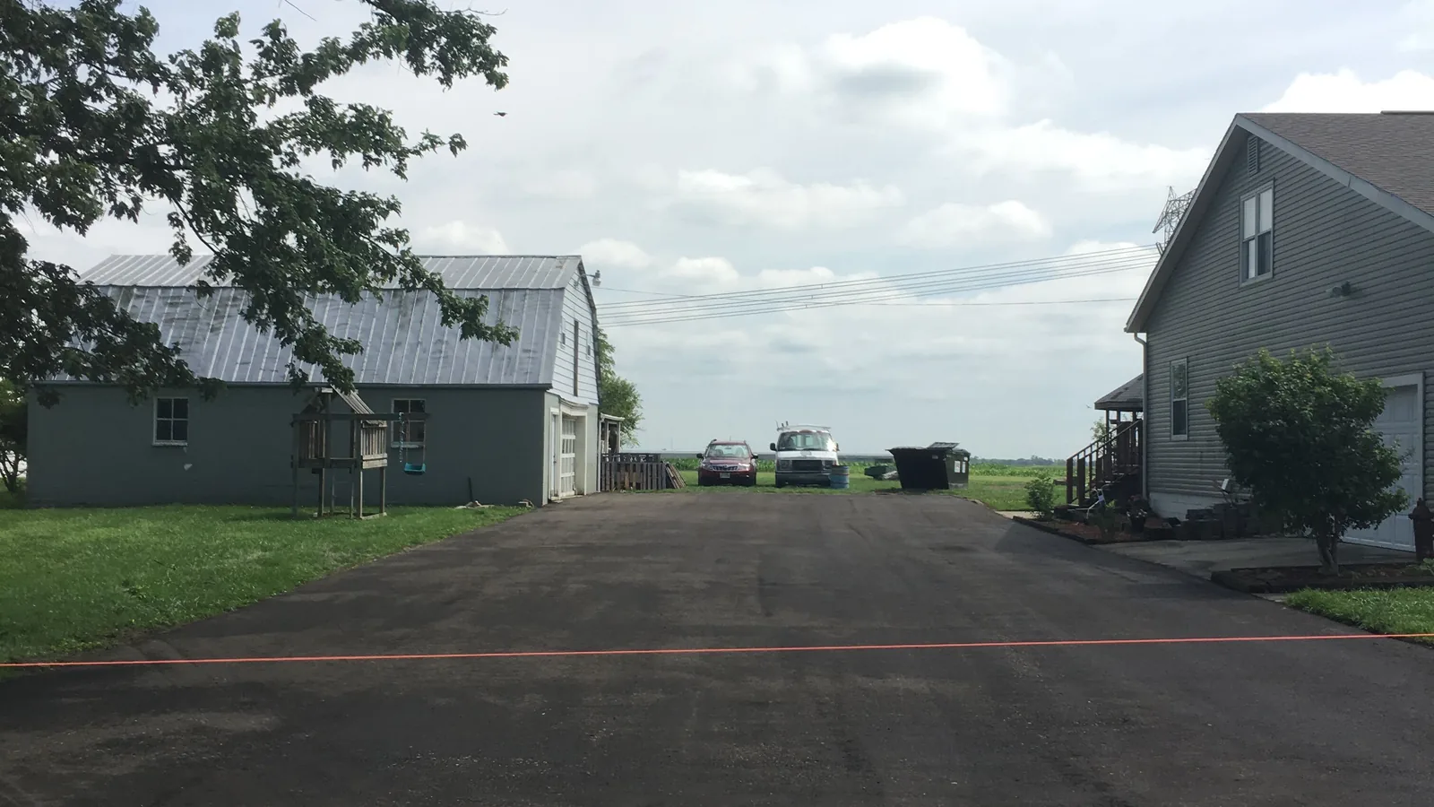 Wide freshly paved drive between a garage and a home
