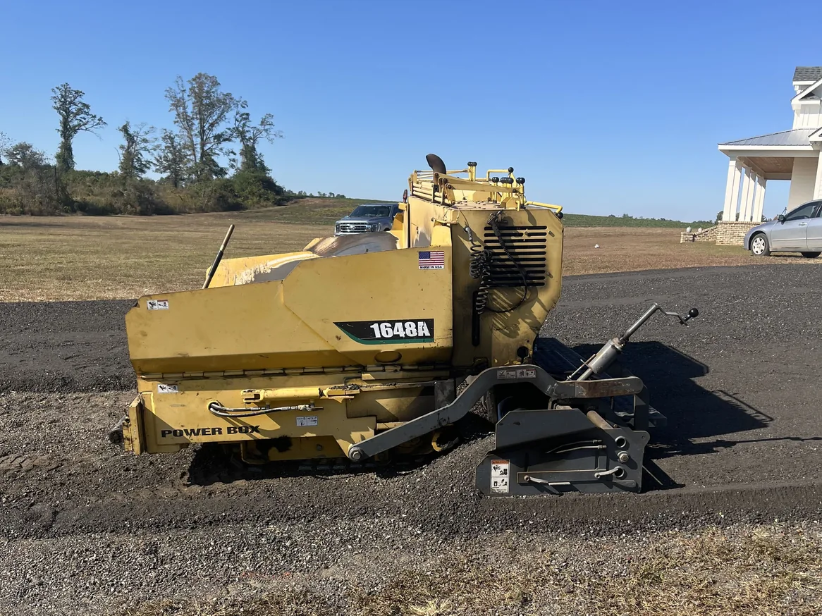 Paving machine on a freshly laid recycled asphalt millings drive by a home