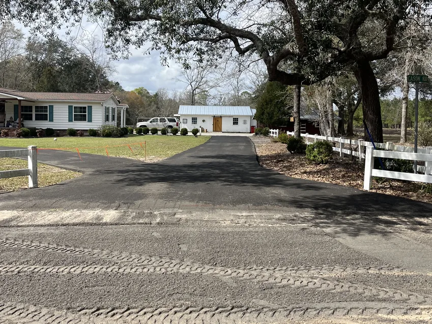 Freshly paved drive by a white fence under a live oak, before any sealcoating
